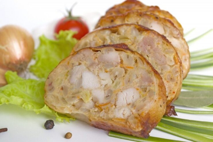 A Perfect Slice of Homemade Chicken Sausage A whole homemade chicken and pearl barley sausage on a plate next to slices and roasted tomatoes.