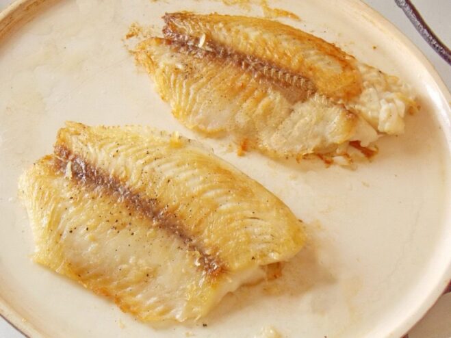 Frying the other side to get a perfect golden-brown crust The fish fillet being fried on the second side in the pan until golden and cooked through.