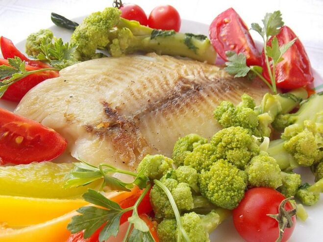 A complete and balanced meal: fried fish with a side of veggies A finished dish of fried ocean perch fillet on a plate, garnished and ready to serve with vegetables.