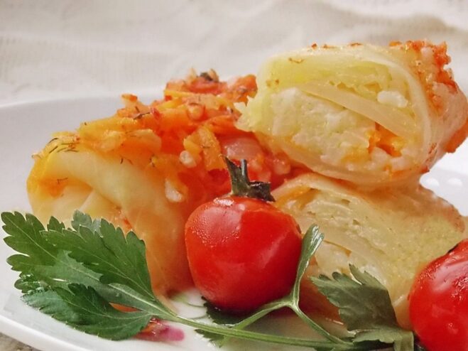 A plate of Lenten vegetable cabbage rolls (golubtsy) served with tomato sauce and fresh herbs.