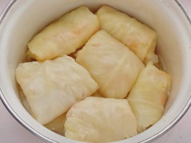 Arranging Cabbage Rolls for Simmering Neatly rolled cabbage rolls (golubtsy) being arranged in a single layer inside a large pot.