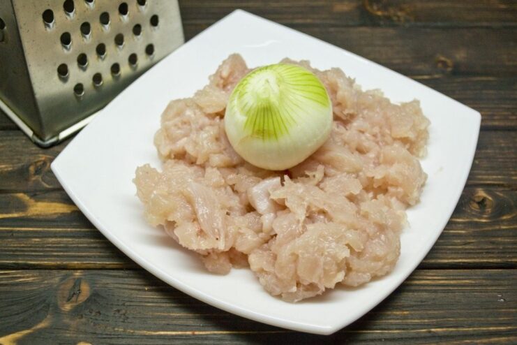 Close-up of minced chicken fillet and grated onion in a bowl for the golubtsy filling.