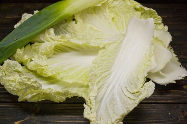 Napa cabbage leaves being blanched in a pot of boiling water.