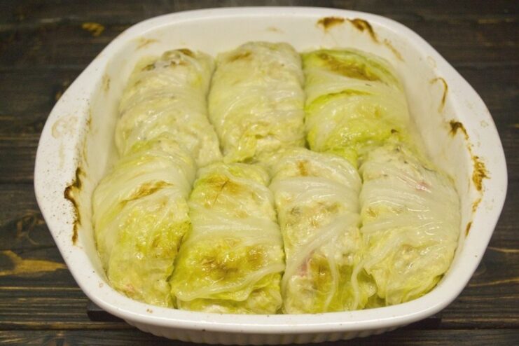 A baking dish with golubtsy cooking inside a hot oven.