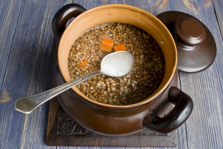 Hot water being poured into the clay pot over the buckwheat and chicken.