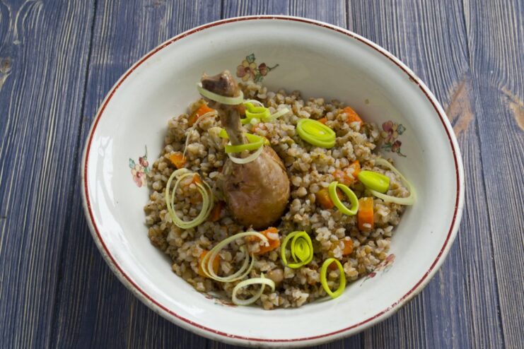 A close-up of the cooked grechka with chicken served on a plate from the clay pot.