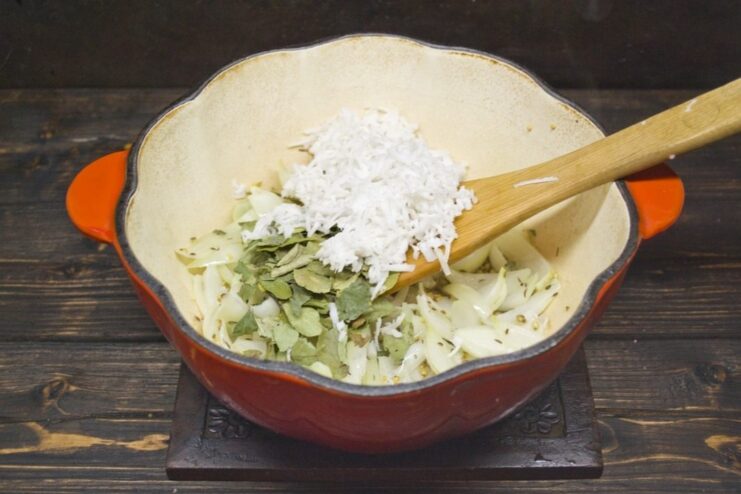 Adding Aromatic Layers: Curry Leaves and Fresh Coconut Adding fresh curry leaves and shredded coconut to the sautéed onions and spices in a pan.
