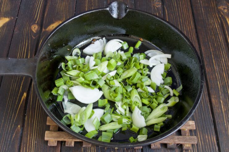 Sautéing finely chopped onions in a pan until translucent. Finely chopped onions being sautéed in a pan with olive oil.