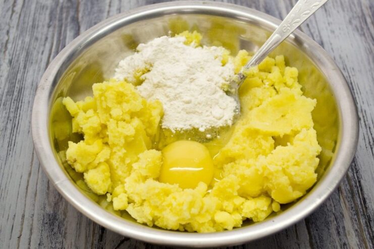 Making the Potato Dough for Zrazy A bowl of mashed potato dough with an egg and flour being mixed.