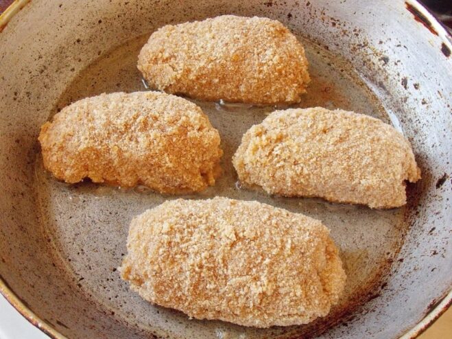 Frying Chicken Kyiv to Golden Perfection Chicken Kyiv cutlets sizzling in a hot pan with oil, starting to turn golden.