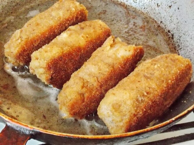Pro Tip: Searing the Sides for Even Cooking Holding a large Chicken Kyiv cutlet with tongs to sear the sides in the hot pan.