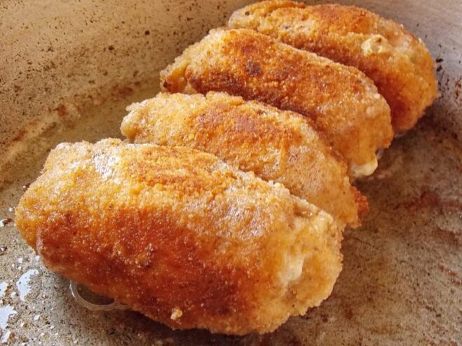 Ensuring an Evenly Cooked, Crispy Exterior Perfectly golden-brown Chicken Kyiv cutlets being fried evenly on all sides in a pan.