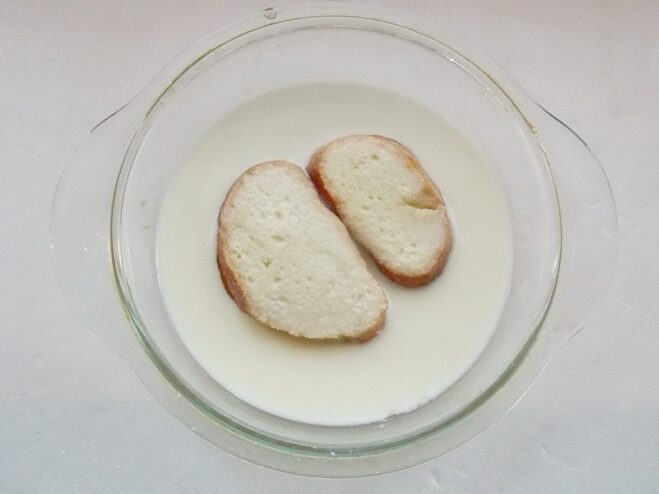 Slices of white bread soaking in a bowl of milk.