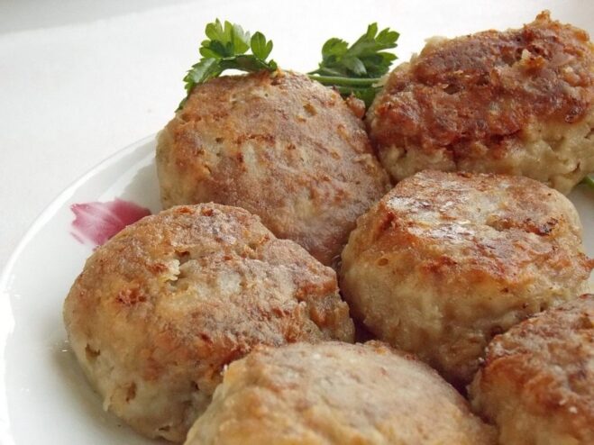 A close-up of juicy, perfectly fried homemade kotlety in a pan.