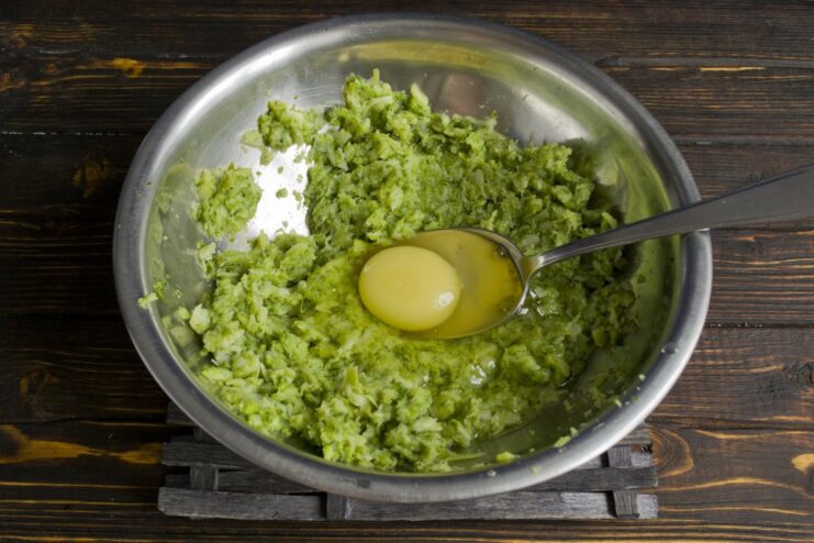 Binding the Broccoli Mixture with Egg and Salt An egg and salt being added to the mashed broccoli mixture.
