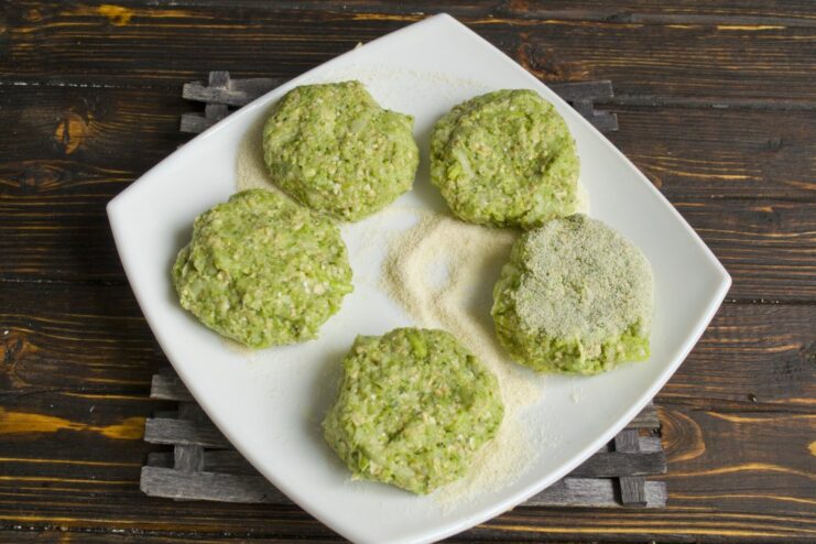 How to Shape and Coat Broccoli Patties A hand shaping a broccoli patty and coating it in a plate of semolina.