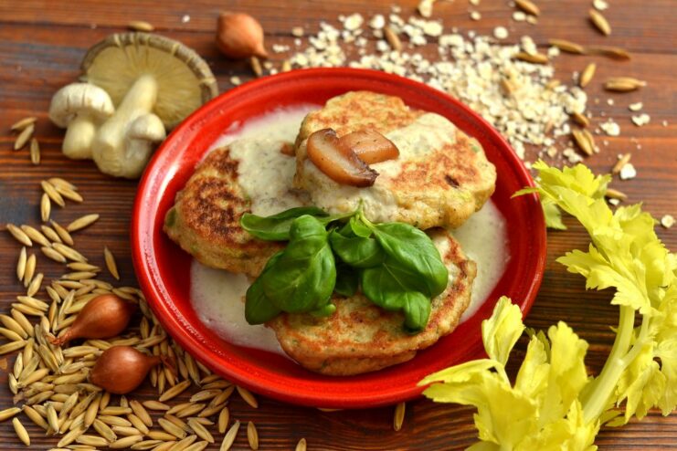 A plate of oatmeal cutlets served with a creamy mushroom gravy and garnished with fresh herbs.
