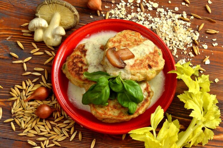 A plate of oatmeal cutlets served with a creamy mushroom gravy and garnished with fresh herbs.