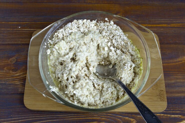 A bowl of rolled oats being soaked in warm broth to soften them for the cutlet mixture.