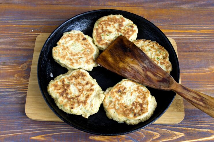 Oatmeal cutlets being fried in a pan until golden brown on both sides.