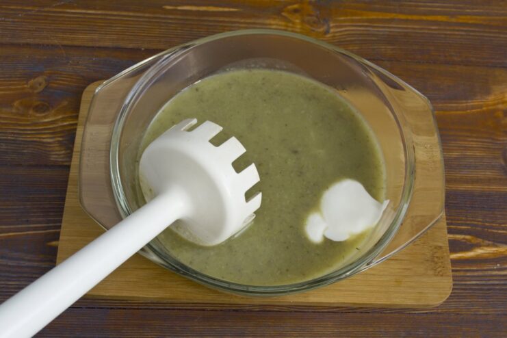 Smetana being added to the sautéed vegetables before blending to create a creamy mushroom gravy.