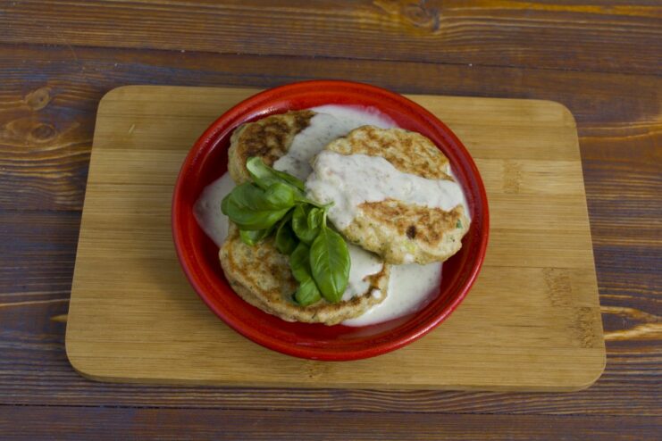 Finished oatmeal cutlets on a plate being generously topped with creamy mushroom gravy.