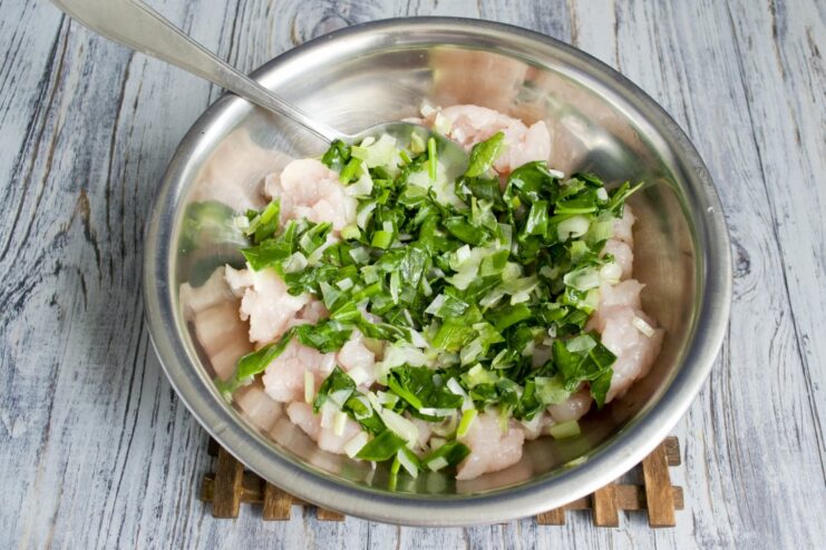 A bowl with ground chicken and a portion of cooled sautéed spinach on top.