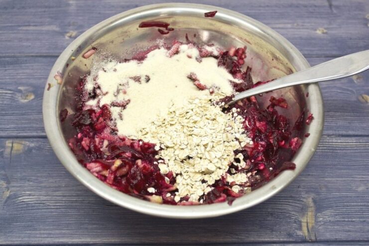 Semolina and rolled oats being added to the beetroot and apple mixture in a bowl.