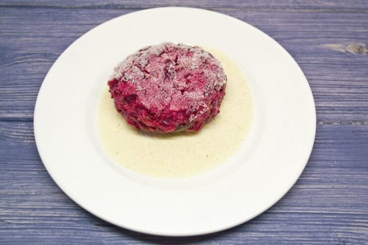 Hand-formed beetroot patties being coated in semolina before frying.