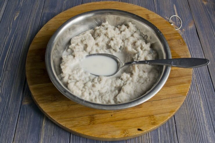 Combining ingredients for the cod fish cake mixture A bowl with minced cod, salt, and milk being mixed together.