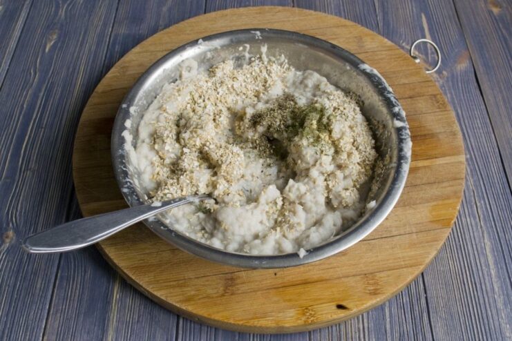 Seasoning the cod fish cake mixture Spices and dried dill being added to the fish cake mixture before mixing.