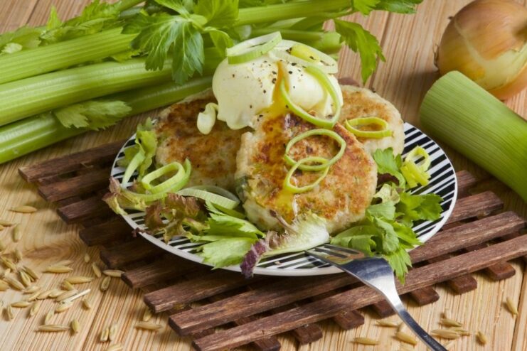 A plate of golden-brown farmer's cheese patties topped with a poached egg and fresh herbs.