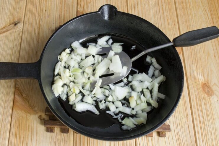 Sautéing finely chopped onion in a pan until translucent. Finely chopped onion being sautéed in a hot frying pan.