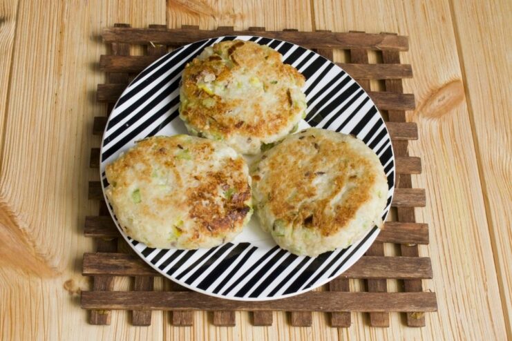 Frying the farmer's cheese patties until they are golden-brown on both sides. Golden-brown farmer's cheese patties being fried in a pan.