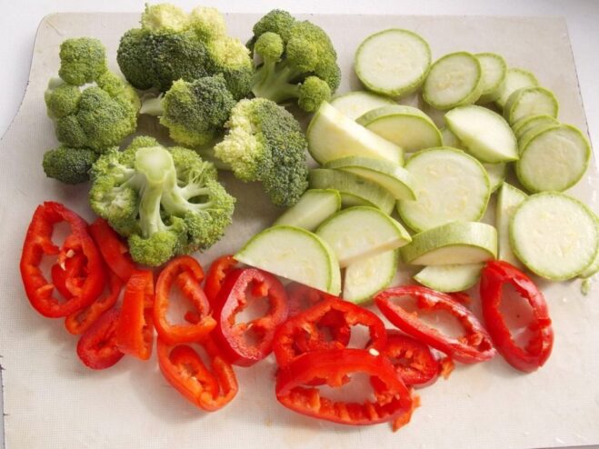 Slicing Fresh Vegetables for Roasting Freshly sliced bell peppers and zucchini on a cutting board, ready for the recipe.