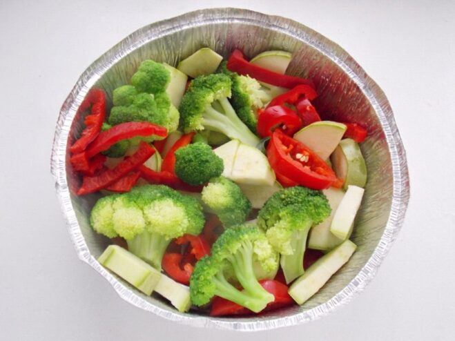 Arranging the Vegetables in a Baking Dish A mix of sliced zucchini, bell peppers, and blanched broccoli arranged in a glass baking dish.