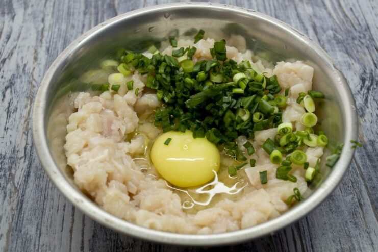 Adding Freshness with Chopped Green Onions A pile of finely chopped green onions being added to the chicken mixture.