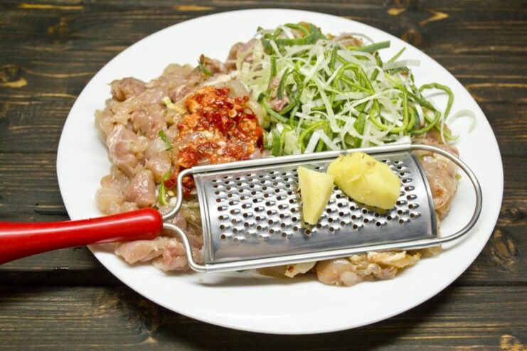 A bowl with finely chopped chicken meat, leeks, and spices for the cutlet filling.