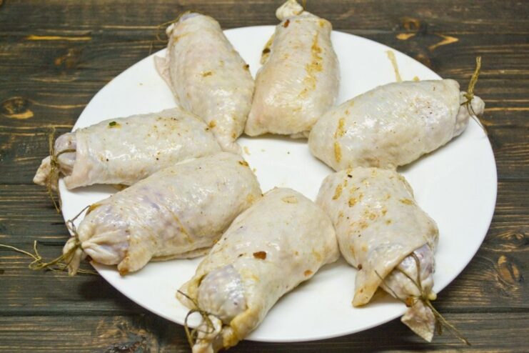 Hands stuffing the chicken skin with the prepared filling to form a cutlet.
