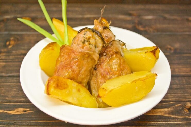 A close-up of the finished chicken cutlets with ginger and chili, served on a plate with potatoes.