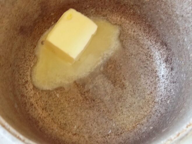 Step 1 for Béchamel: Melting butter in a saucepan A piece of butter melting in a dark-colored saucepan over low heat.