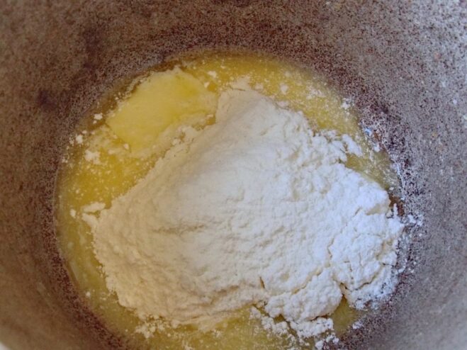 Creating the roux by adding flour to the melted butter Adding all-purpose flour to the melted butter in a saucepan to make a roux.