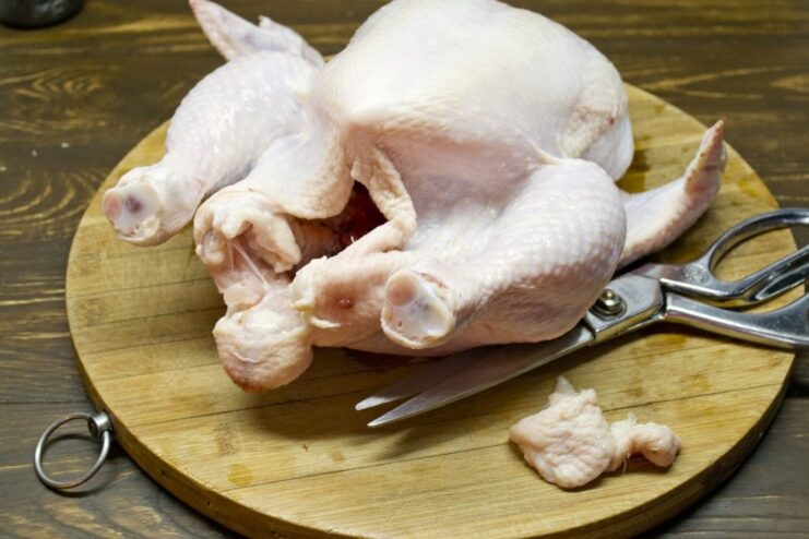 Step-by-step: How to prepare a whole chicken for roasting. A raw whole chicken being patted dry with paper towels on a cutting board.