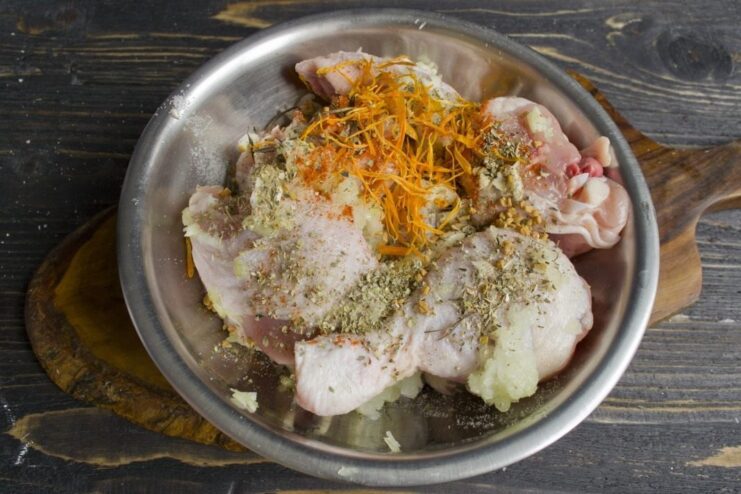 Coating the chicken with a blend of aromatic spices for marination. Spices being sprinkled and rubbed onto raw chicken pieces in a bowl.