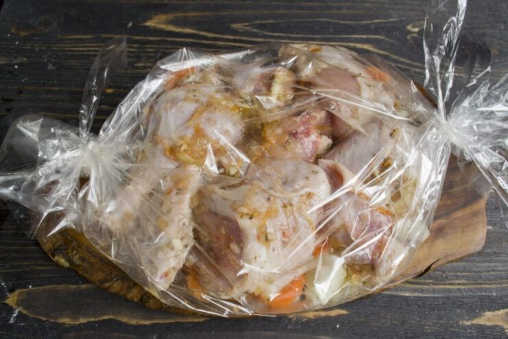Securing the oven bag to lock in moisture and flavor before baking. A sealed oven bag with chicken and vegetables on a baking sheet, ready for the oven.