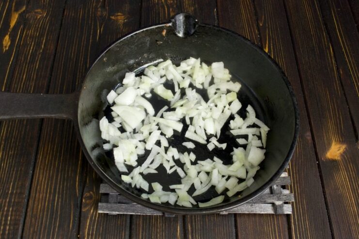Sautéing Finely Chopped Onions for the Machanka Base Finely chopped onions being sautéed in a cast-iron skillet until translucent.