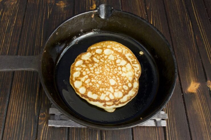 Frying Golden Corn Pancakes in a Skillet A golden-brown corn pancake being fried in a hot, oiled cast-iron skillet.