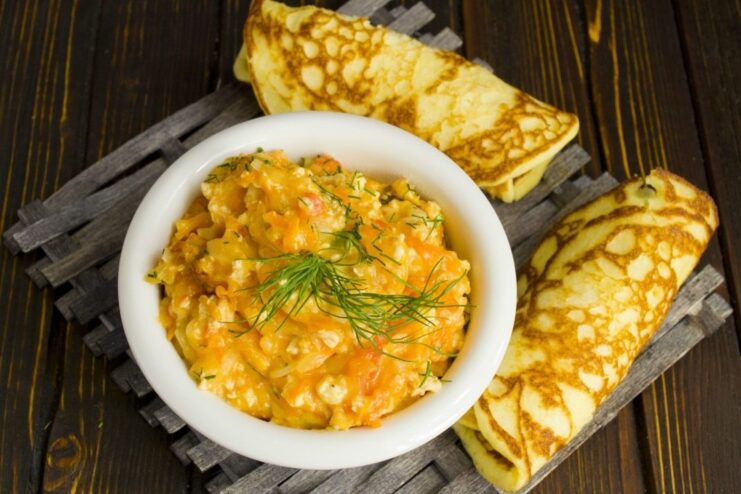 The Final Dish: Chicken Machanka Served with Corn Pancakes A serving of creamy chicken machanka in a bowl next to a stack of freshly made corn pancakes.