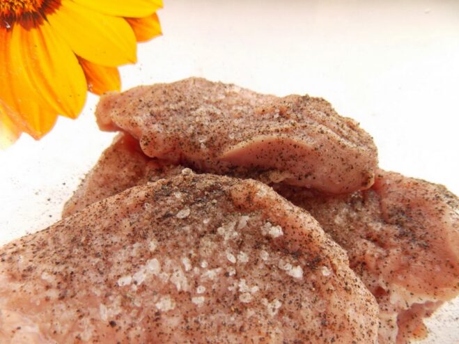 Step 1: Preparing and seasoning the pork medallions Raw pork slices in a bowl being seasoned with salt and pepper.