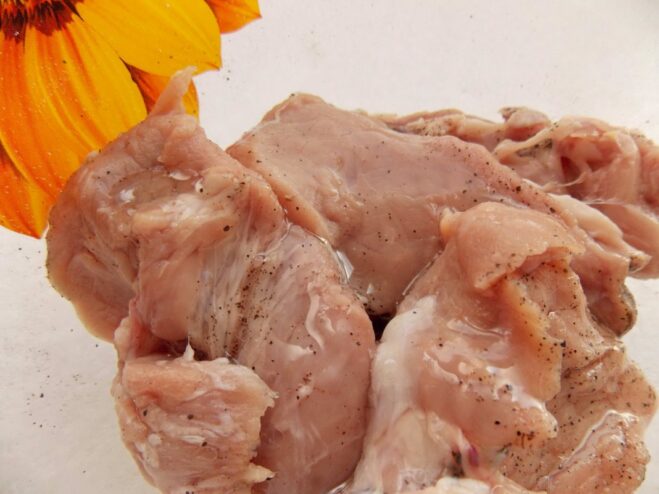 Step 2: Coating the seasoned pork with oil before searing Seasoned pork medallions in a bowl being coated with sunflower oil.